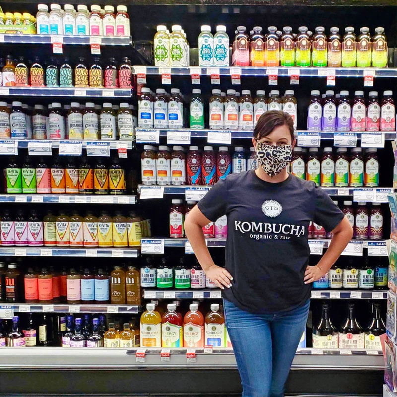 Kombucha rep in front of their products in a store